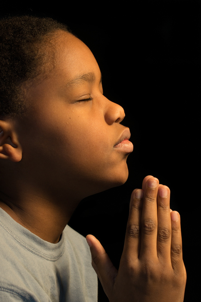 Young boy with his hands held in prayer